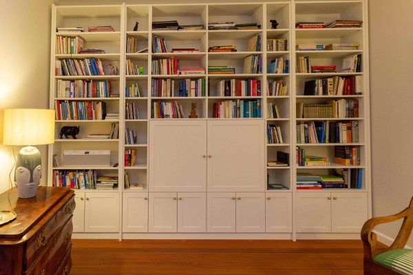 Bücherregal, weiß lackiert, mit geschlossenen Fächern unten und Türen vor dem Fernsehgerät. Geplant und hergestellt von der Schreinerei Freymark in Freiburg