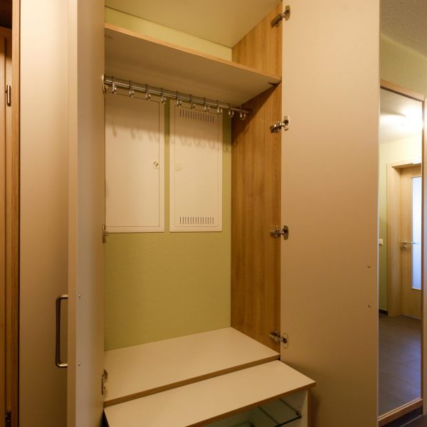 Einbaugarderobe mit ausziehbarem Schuhregal vor dem Heizverteiler und abnehmbarer Kleiderstange vor dem Sicherungskasten